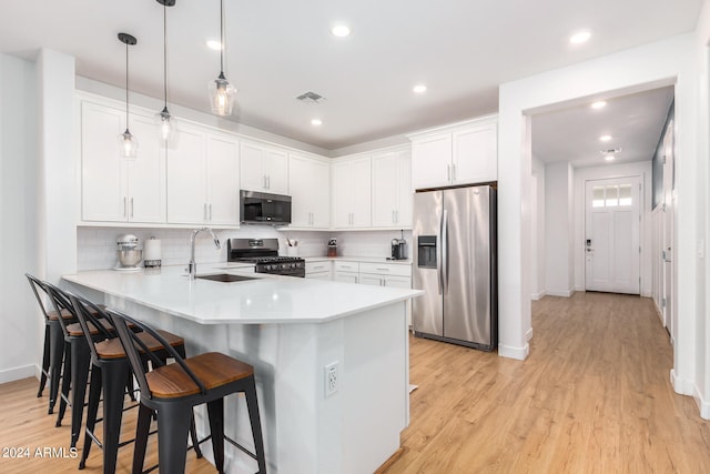 kitchen featuring hanging light fixtures, kitchen peninsula, sink, white cabinetry, and appliances with stainless steel finishes