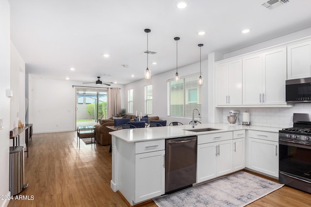 kitchen with sink, appliances with stainless steel finishes, hanging light fixtures, and white cabinets