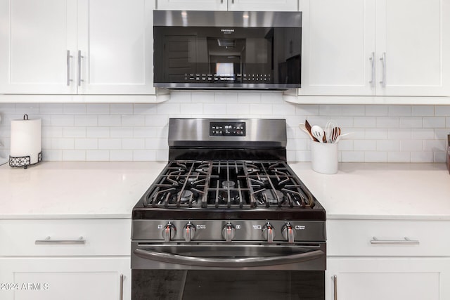 kitchen with appliances with stainless steel finishes, white cabinetry, and light stone counters