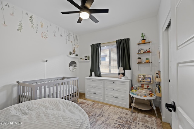 bedroom with a nursery area and ceiling fan