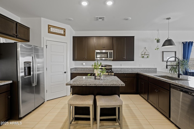 kitchen featuring light tile patterned floors, a breakfast bar area, light stone countertops, and appliances with stainless steel finishes