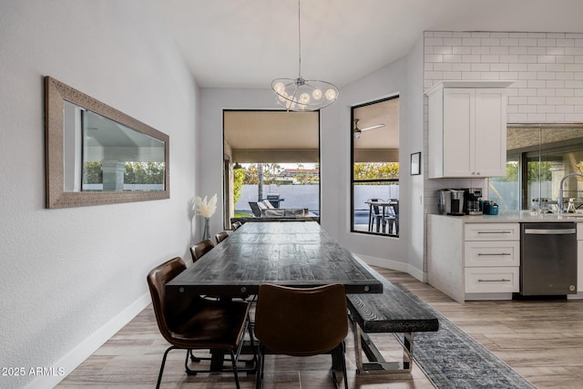 dining space with a notable chandelier, a wealth of natural light, light hardwood / wood-style flooring, and sink