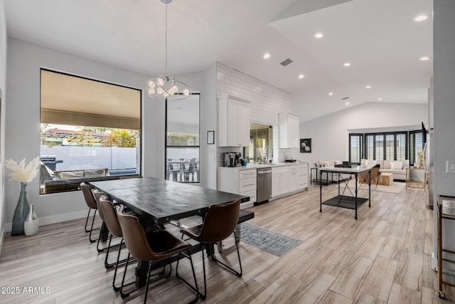 dining area with lofted ceiling, sink, a wealth of natural light, and light wood-type flooring