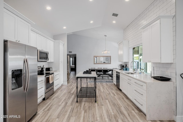 kitchen with stainless steel appliances, sink, white cabinets, and decorative light fixtures