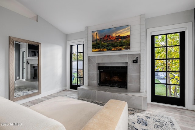 living room featuring vaulted ceiling, a fireplace, and light hardwood / wood-style flooring