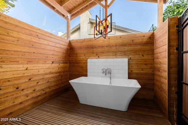 bathroom featuring beam ceiling, a skylight, wooden walls, high vaulted ceiling, and a bathing tub