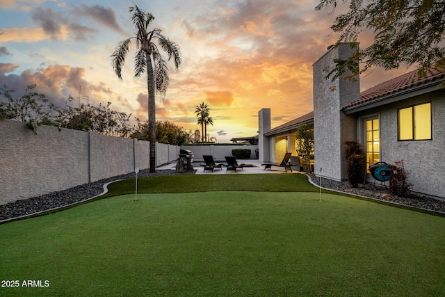 yard at dusk featuring a patio