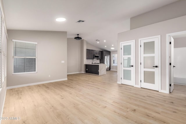 unfurnished living room featuring lofted ceiling and light hardwood / wood-style floors