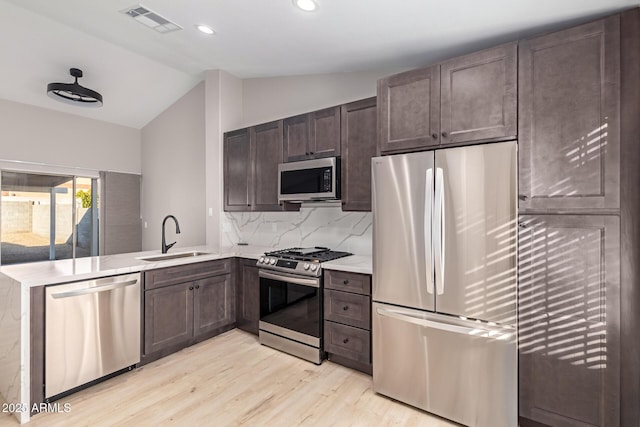 kitchen with tasteful backsplash, lofted ceiling, sink, kitchen peninsula, and stainless steel appliances