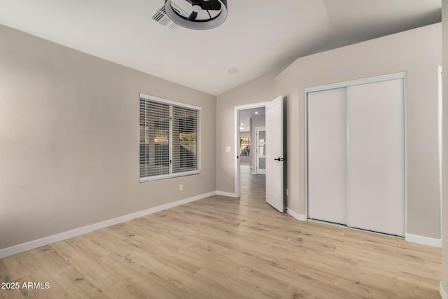 unfurnished bedroom with lofted ceiling, light hardwood / wood-style floors, and a closet