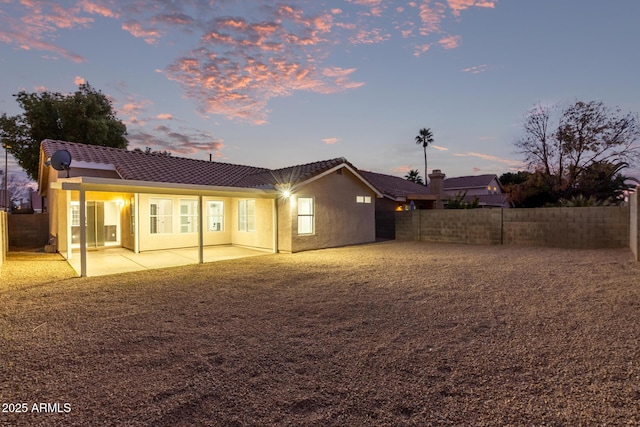 back house at dusk featuring a patio area