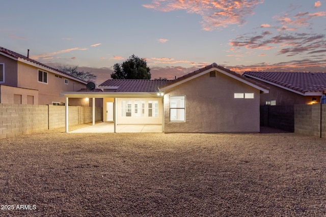 back house at dusk featuring a patio area