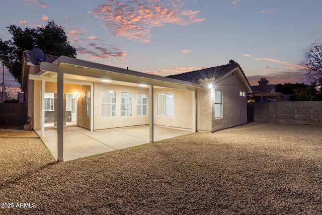 back house at dusk with a patio area