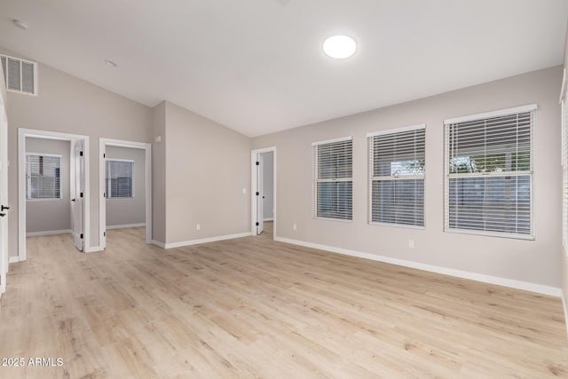 spare room with vaulted ceiling and light wood-type flooring