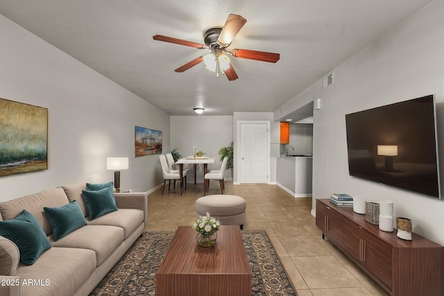 living area featuring baseboards, visible vents, ceiling fan, and light tile patterned flooring