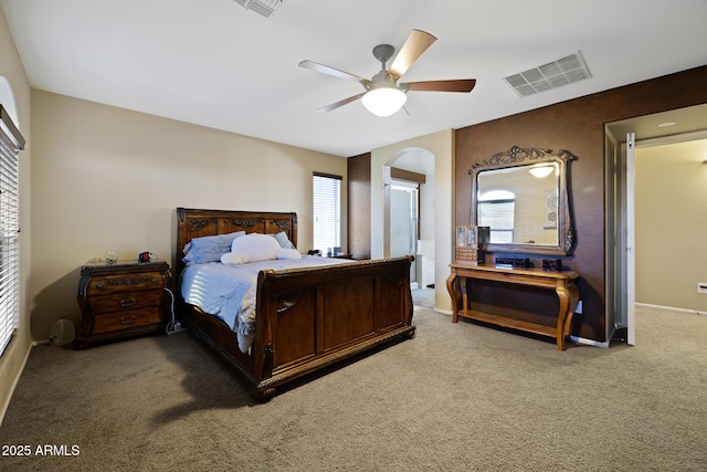 bedroom featuring visible vents, arched walkways, ceiling fan, and carpet flooring