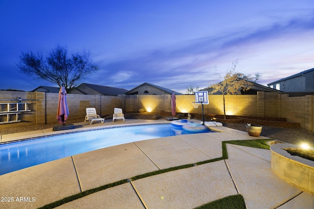 pool at dusk featuring a pool with connected hot tub, a fenced backyard, and a patio area