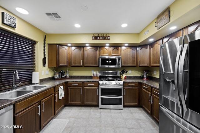 kitchen with visible vents, light tile patterned flooring, a sink, appliances with stainless steel finishes, and dark countertops