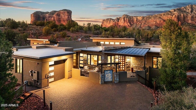 view of front facade featuring an attached garage, a standing seam roof, metal roof, a mountain view, and stone siding