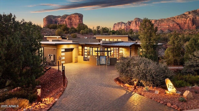 view of front of home featuring metal roof, an attached garage, a mountain view, decorative driveway, and a standing seam roof