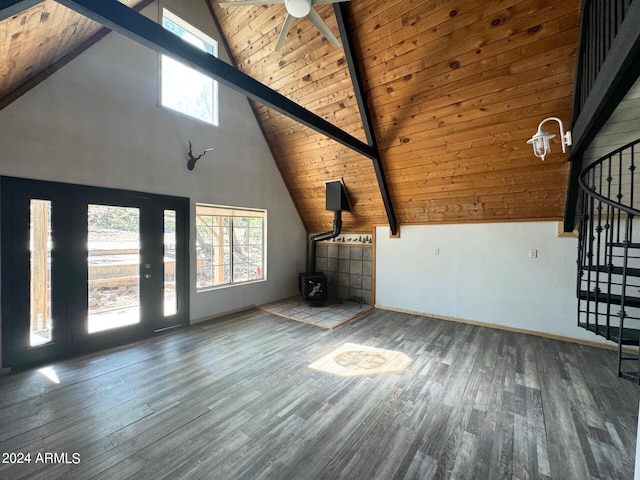 unfurnished living room with ceiling fan, beamed ceiling, a wood stove, wooden ceiling, and hardwood / wood-style floors