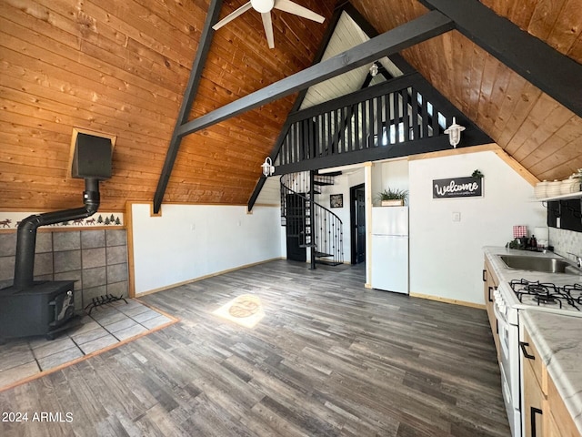 kitchen featuring dark wood-type flooring, beam ceiling, a wood stove, and white appliances