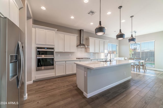 kitchen featuring white cabinetry, sink, wall chimney exhaust hood, pendant lighting, and appliances with stainless steel finishes