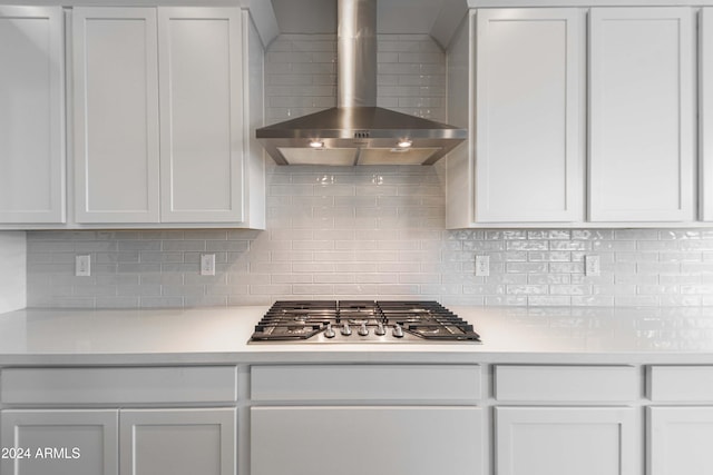 kitchen featuring wall chimney exhaust hood, white cabinetry, stainless steel gas cooktop, and tasteful backsplash