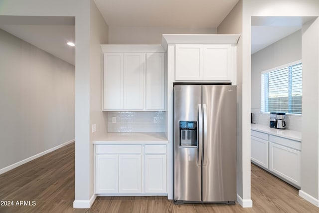 kitchen with stainless steel fridge, light hardwood / wood-style flooring, and white cabinets