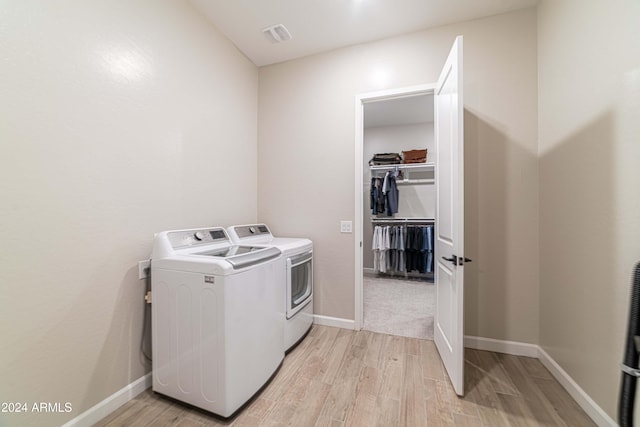 laundry room featuring washer and clothes dryer and light hardwood / wood-style floors