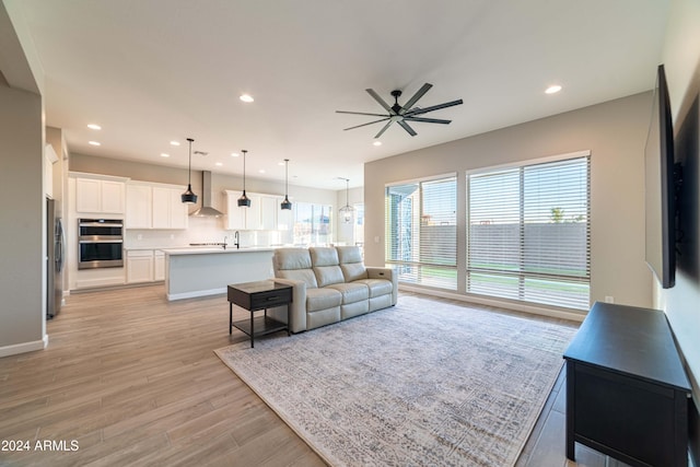 living room featuring light hardwood / wood-style floors, ceiling fan, and sink