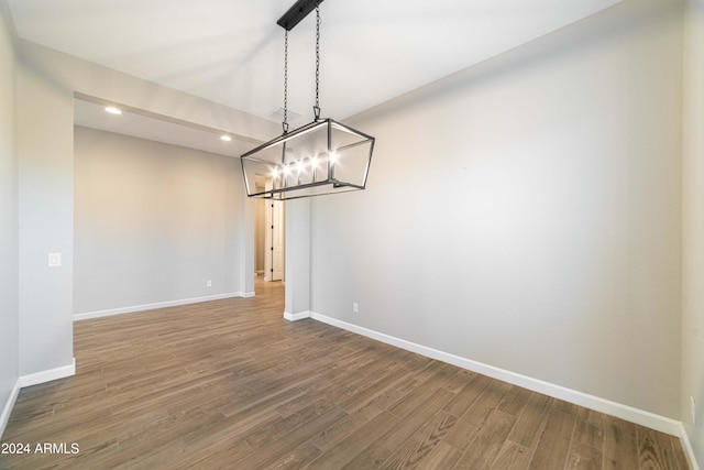 unfurnished dining area featuring a chandelier and wood-type flooring