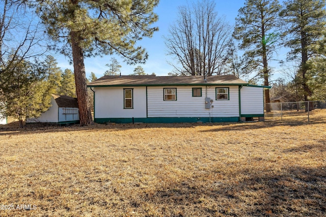 rear view of house featuring a storage unit and a yard