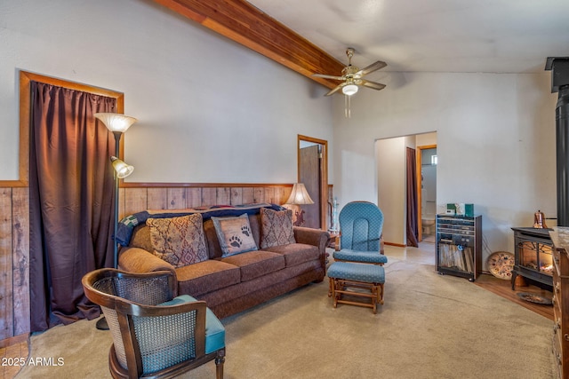 carpeted living room with vaulted ceiling with beams, ceiling fan, and a wood stove