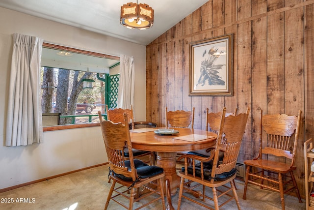 dining area with wooden walls, vaulted ceiling, and carpet flooring