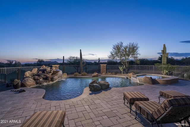 9161 E Superstition Mountain Dr, Gold Canyon, AZ 85118 - pool at dusk featuring pool water feature, a patio, and an in ground hot tub