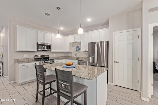 kitchen with appliances with stainless steel finishes, hanging light fixtures, and white cabinets