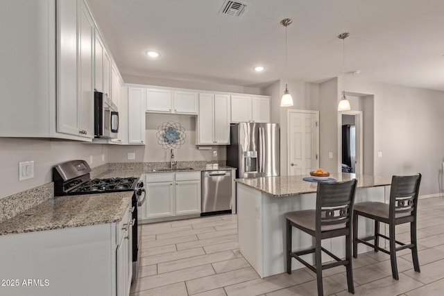 kitchen featuring a kitchen island, stainless steel appliances, sink, and white cabinetry