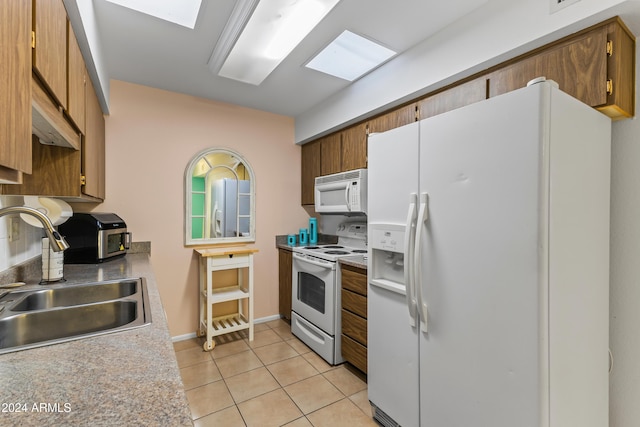 kitchen featuring white appliances, sink, and light tile patterned floors