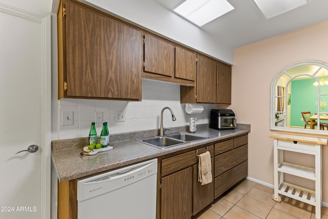 kitchen featuring white dishwasher, decorative backsplash, light tile patterned floors, and sink