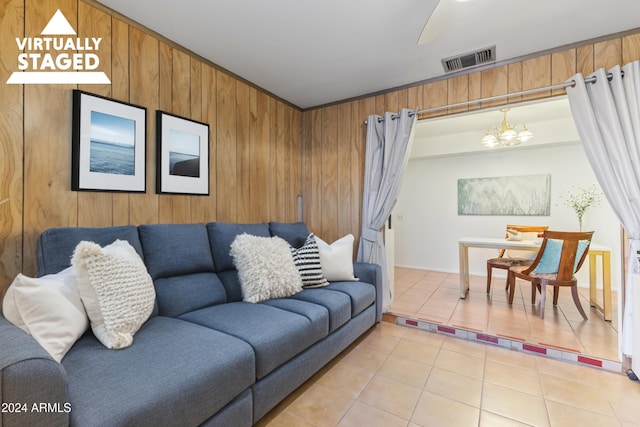 living room featuring an inviting chandelier, tile patterned floors, and wood walls