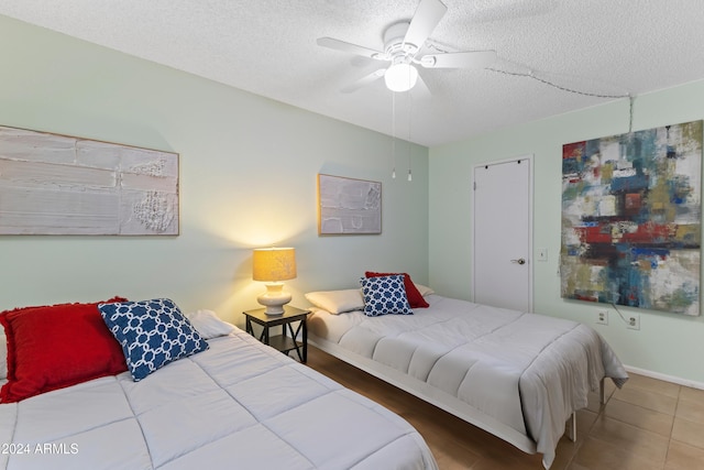 bedroom with tile patterned floors, ceiling fan, and a textured ceiling