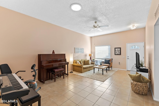 living room featuring ceiling fan, light tile patterned flooring, and a textured ceiling