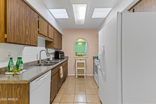 kitchen with backsplash, sink, light tile patterned floors, and white appliances