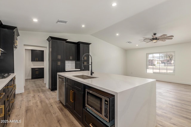 kitchen with ceiling fan, sink, light hardwood / wood-style flooring, an island with sink, and stainless steel appliances