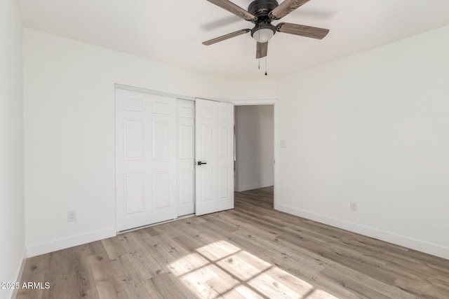 unfurnished bedroom featuring ceiling fan, a closet, and light wood-type flooring