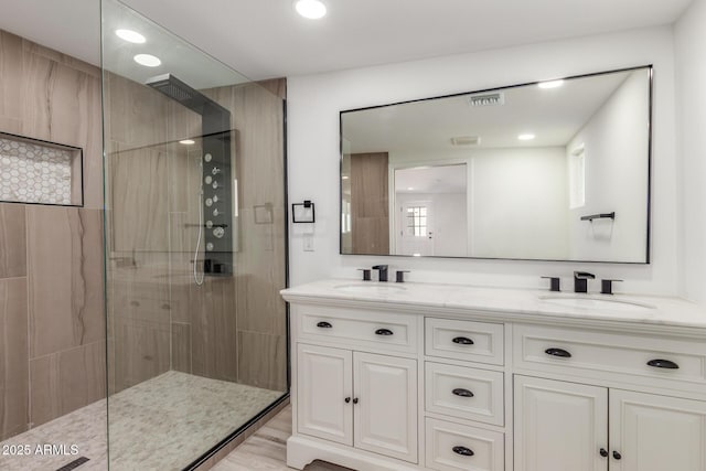 bathroom featuring wood-type flooring, vanity, and a tile shower