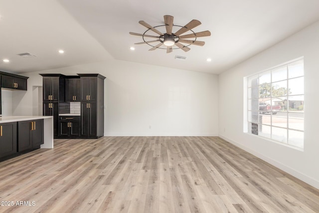 unfurnished living room with ceiling fan, vaulted ceiling, and light wood-type flooring