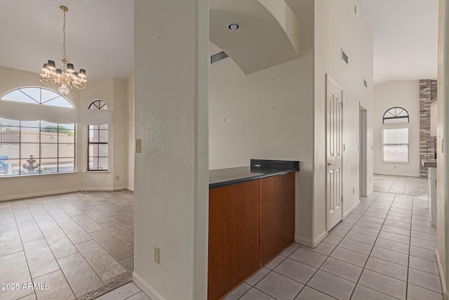 kitchen featuring decorative light fixtures, light tile patterned floors, a notable chandelier, and a towering ceiling