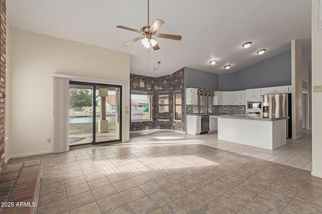 unfurnished living room with ceiling fan, light tile patterned floors, high vaulted ceiling, and white cabinets